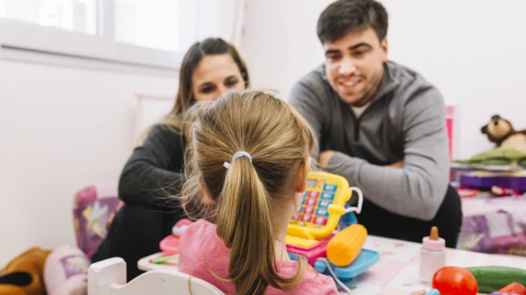 Parents observe their child during a daycare visit in a bright classroom