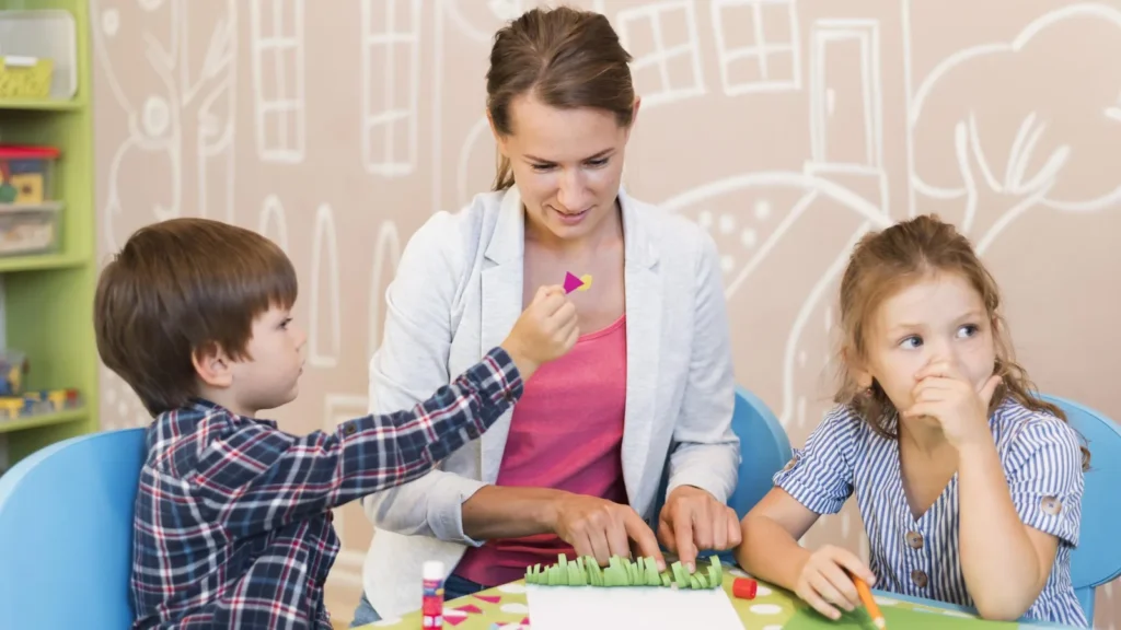 Preschool teacher guides two young children during a hands-on classroom activity