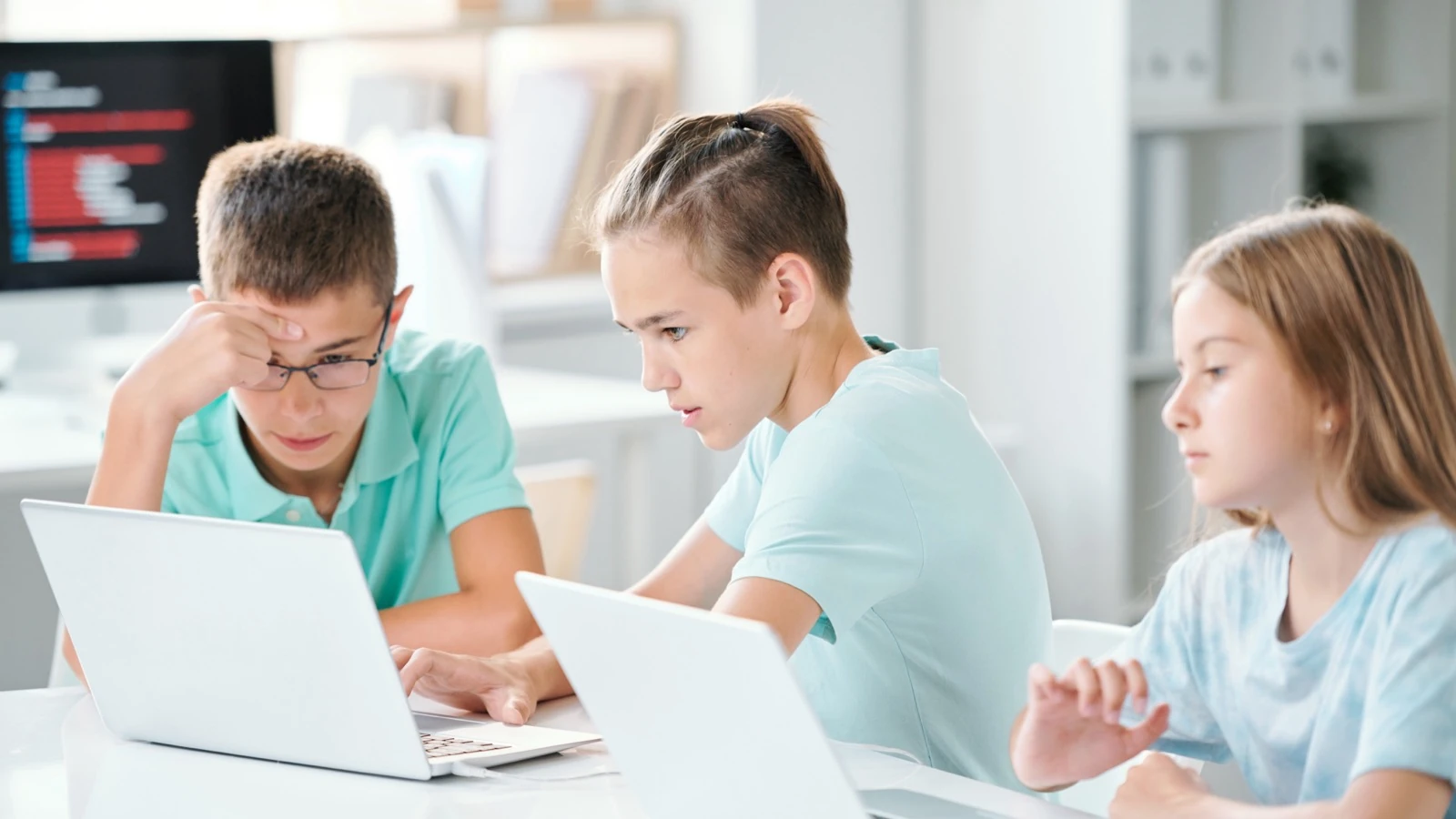 School-age children working together on laptop projects in a bright classroom