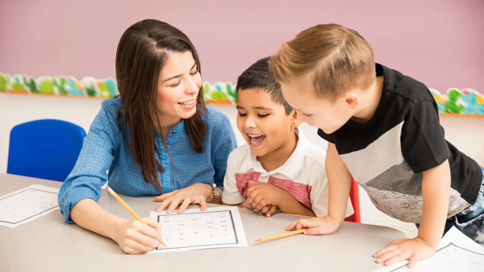 Preschool teacher working with two children at a classroom table in Irving TX
